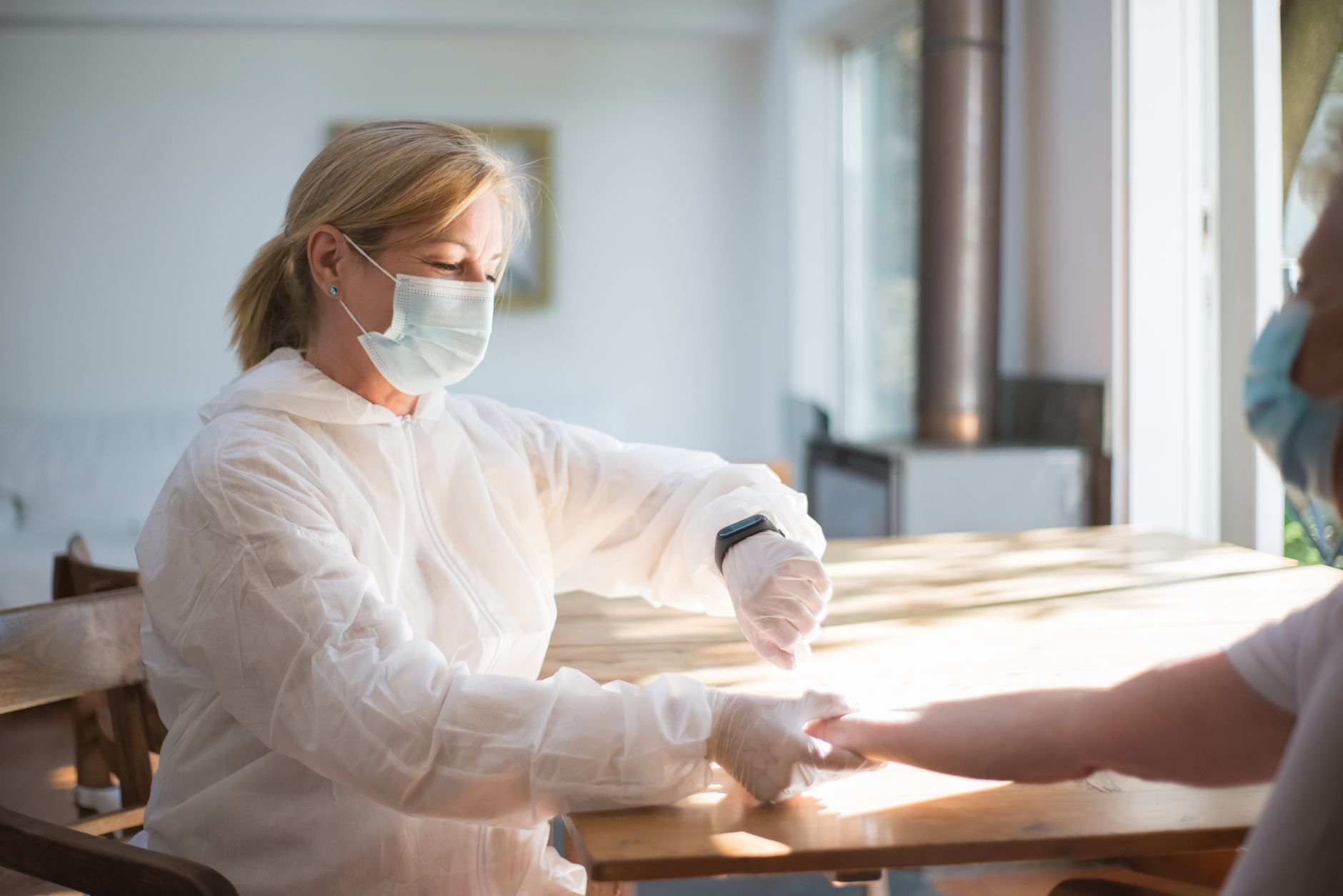 Healthcare professional in protective gear attending to a patient indoors, showcasing modern medical practices.