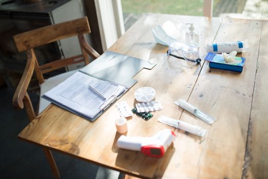 A spread of medical supplies and COVID-19 essentials on a sunlit wooden table.