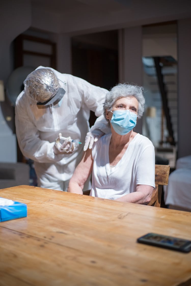 A Medical Professional Injecting An Elderly Woman