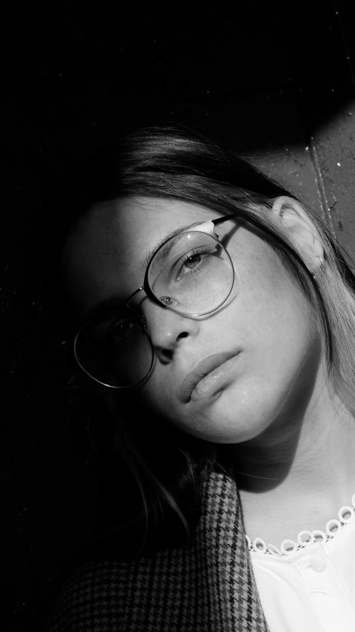 Free Artistic black and white portrait of a woman in glasses with dramatic shadows. Stock Photo