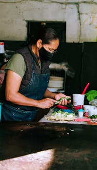 A masked woman in Puebla prepares Mexican cuisine, showcasing cultural culinary skills.