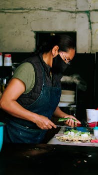 A woman in Puebla, Mexico prepares traditional Mexican food indoors, wearing an apron and face mask.