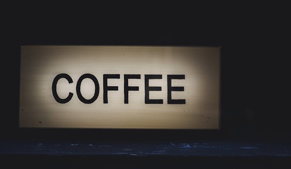 A glowing coffee sign stands out against a dark background, creating a warm and inviting atmosphere.