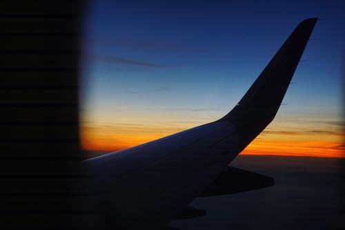 Free Silhouette of an airplane wing during sunset, capturing vibrant sky colors. Stock Photo