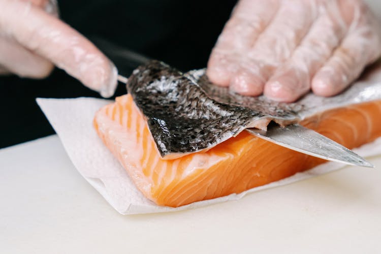 A Person Removing The Skin Of A Salmon