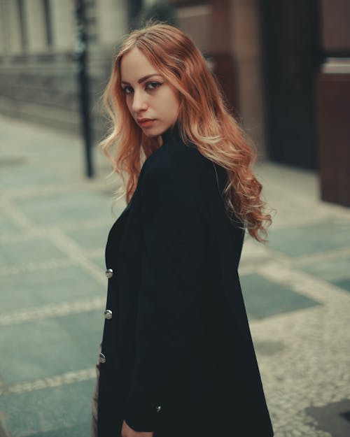 Photo of a Woman in a Black Coat Looking at the Camera