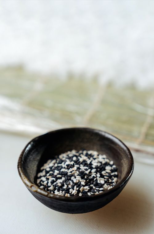 Free Aesthetic close-up of black and white sesame seeds in a ceramic bowl on a textured surface. Stock Photo