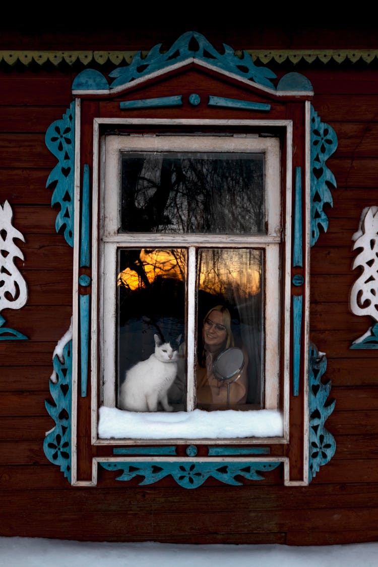 Woman With Cat In Window Of Rustic House