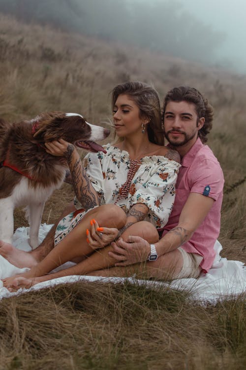 Couple Sitting on Grass with their Dog