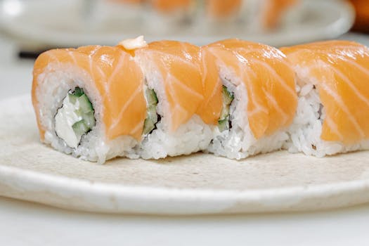 Close-up of salmon sushi roll with rice and cucumber on a plate.