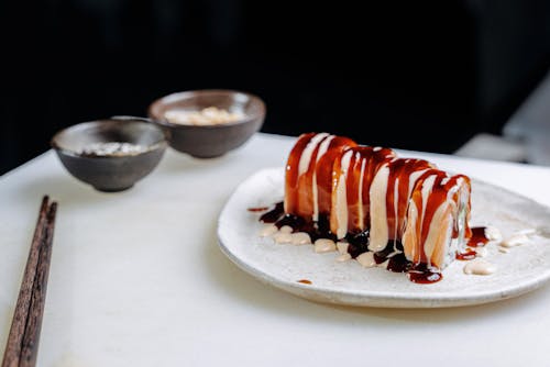 A Plate of Salmon Sushi Rolls with White and Brown Sauce