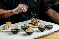 Chef crafting sushi with precision, showcasing gourmet elegance in a modern restaurant setting.