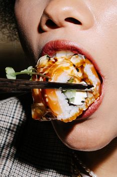 Detailed close-up of a person savoring sushi using chopsticks, highlighting culinary culture.