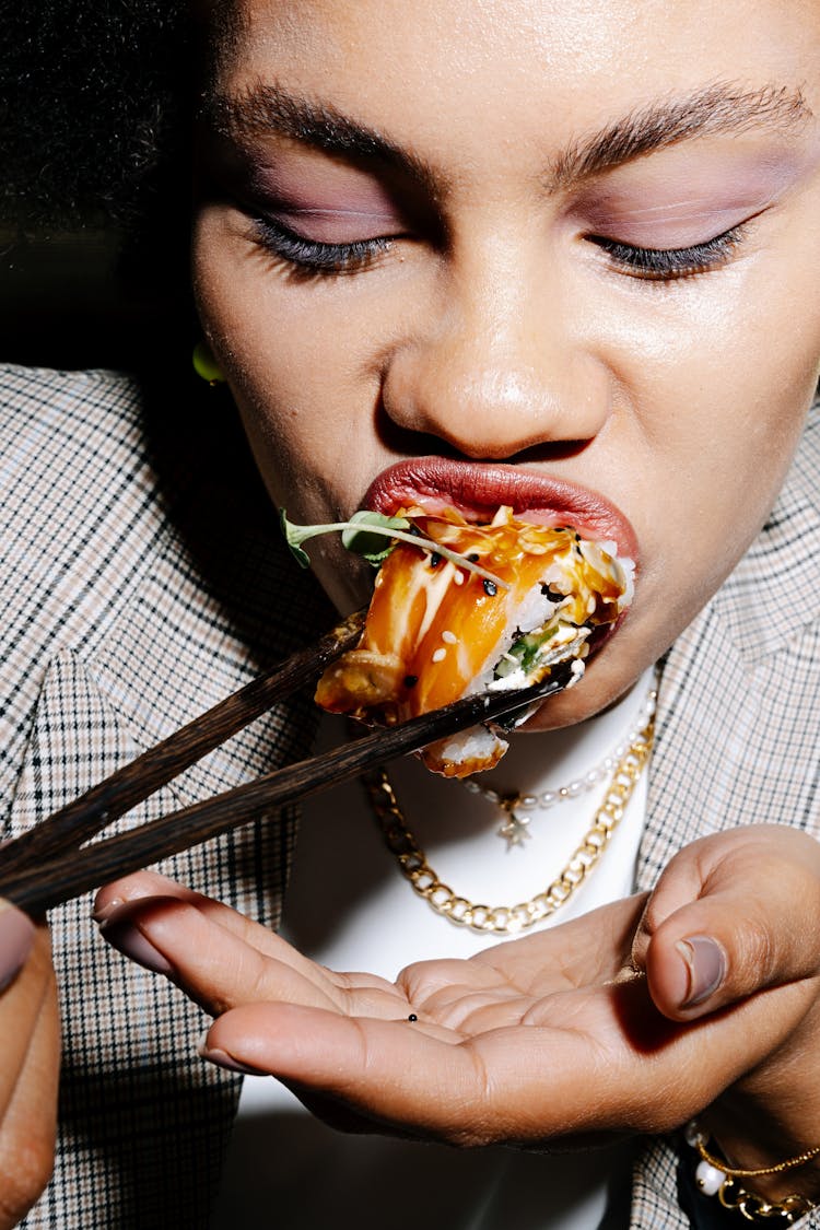 Person Eating Sushi With Black Chopsticks