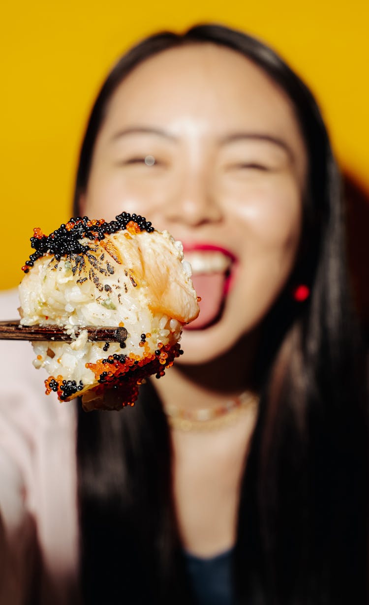 Woman Holding Sushi With Chopsticks