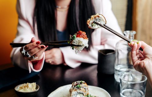 Free Two women enjoying sushi with chopsticks in an elegant restaurant setting. Stock Photo
