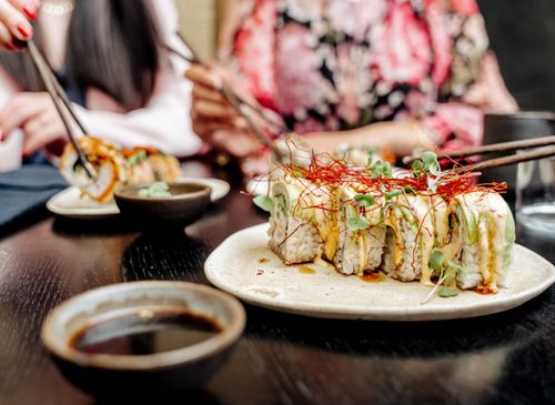 Free Delicious sushi rolls with garnish served on a plate at a dining table. Stock Photo