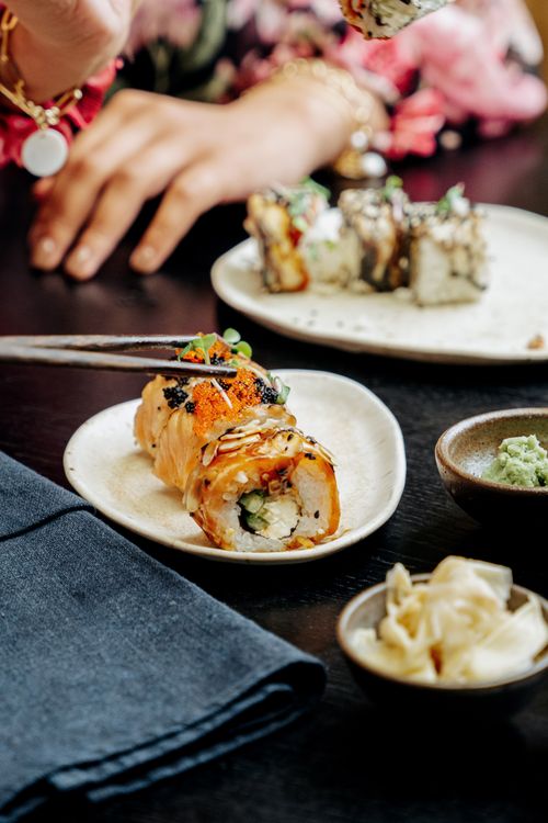 Free Close-up view of a sushi platter with vibrant ingredients and chopsticks on a dining table. Stock Photo