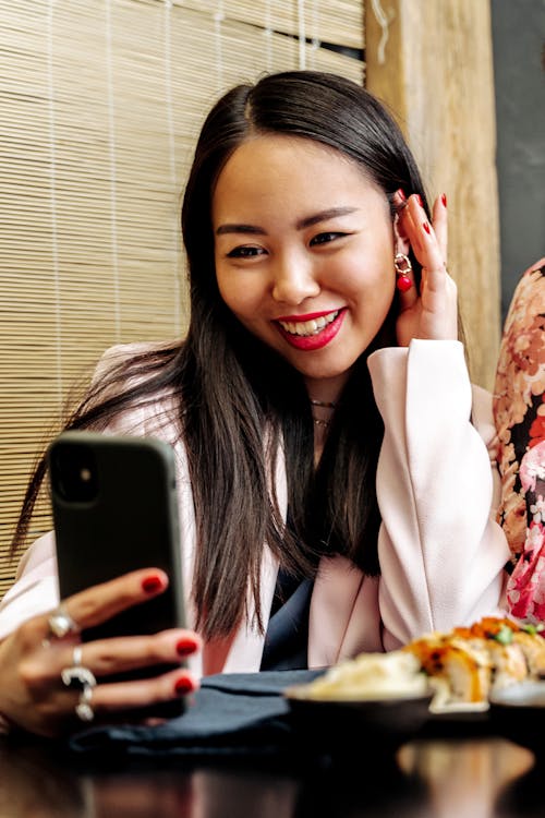 Free Woman in Pink Blazer Holding a Black Smartphone Stock Photo