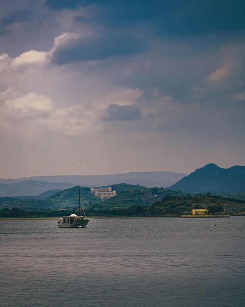 Free Peaceful sailboat on Lake Pichola with scenic mountain backdrop in Udaipur, India. Stock Photo