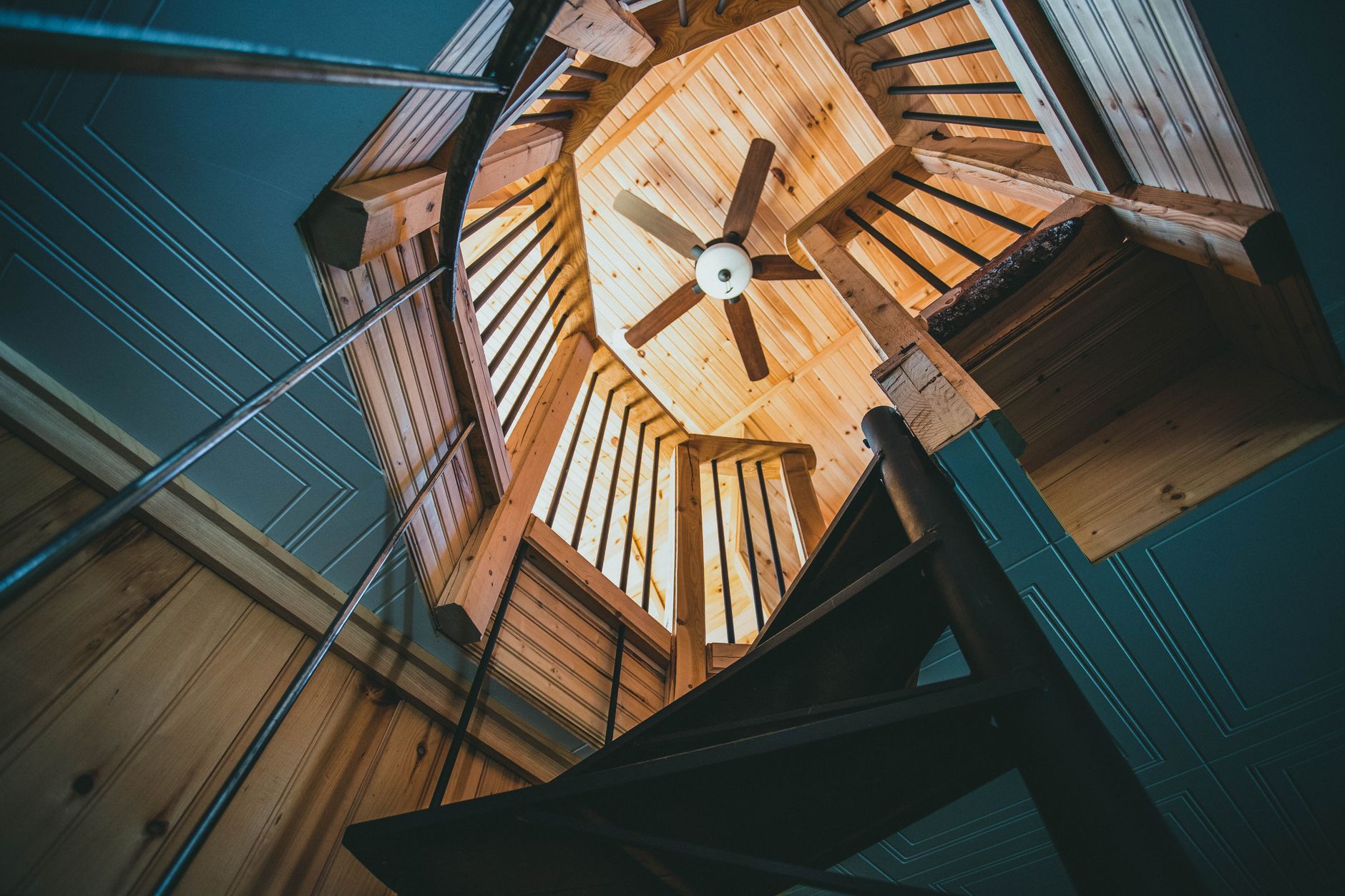 Low-angle view of a modern wooden spiral staircase in a house interior.