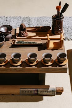 A traditional tea ceremony setup featuring pottery cups, tools, and a wooden tray capturing the essence of tea culture.