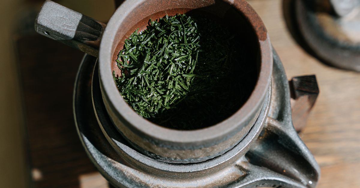 Close-up of a rustic clay teapot filled with dry green tea leaves, highlighting its texture and detail. - Evidence evidence guide for green tea extract fat oxidation randomized trial