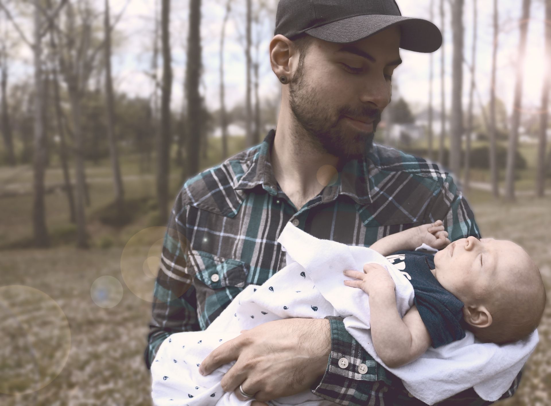 A father lovingly holds his newborn child outdoors, capturing a tender parenting moment.