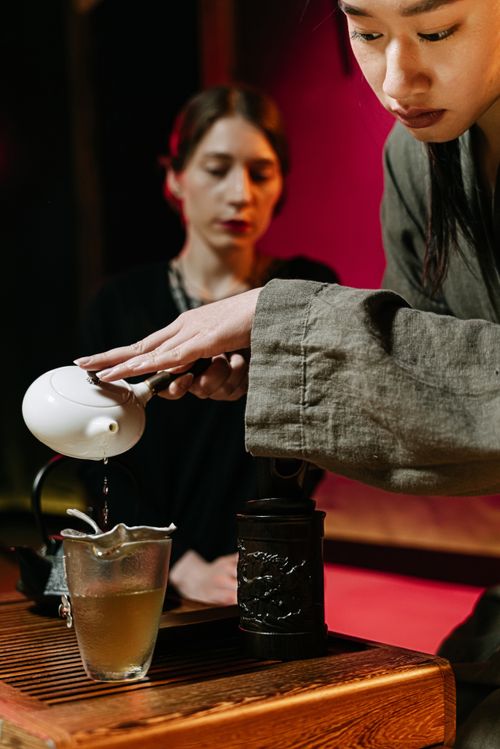 Free An authentic tea ceremony showing a woman pouring tea with precision, emphasizing the art of tea making. Stock Photo