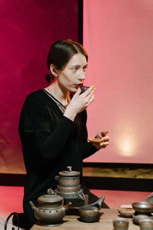 Free Woman savoring a cup of tea in a cozy, warmly lit setting indoors. Stock Photo