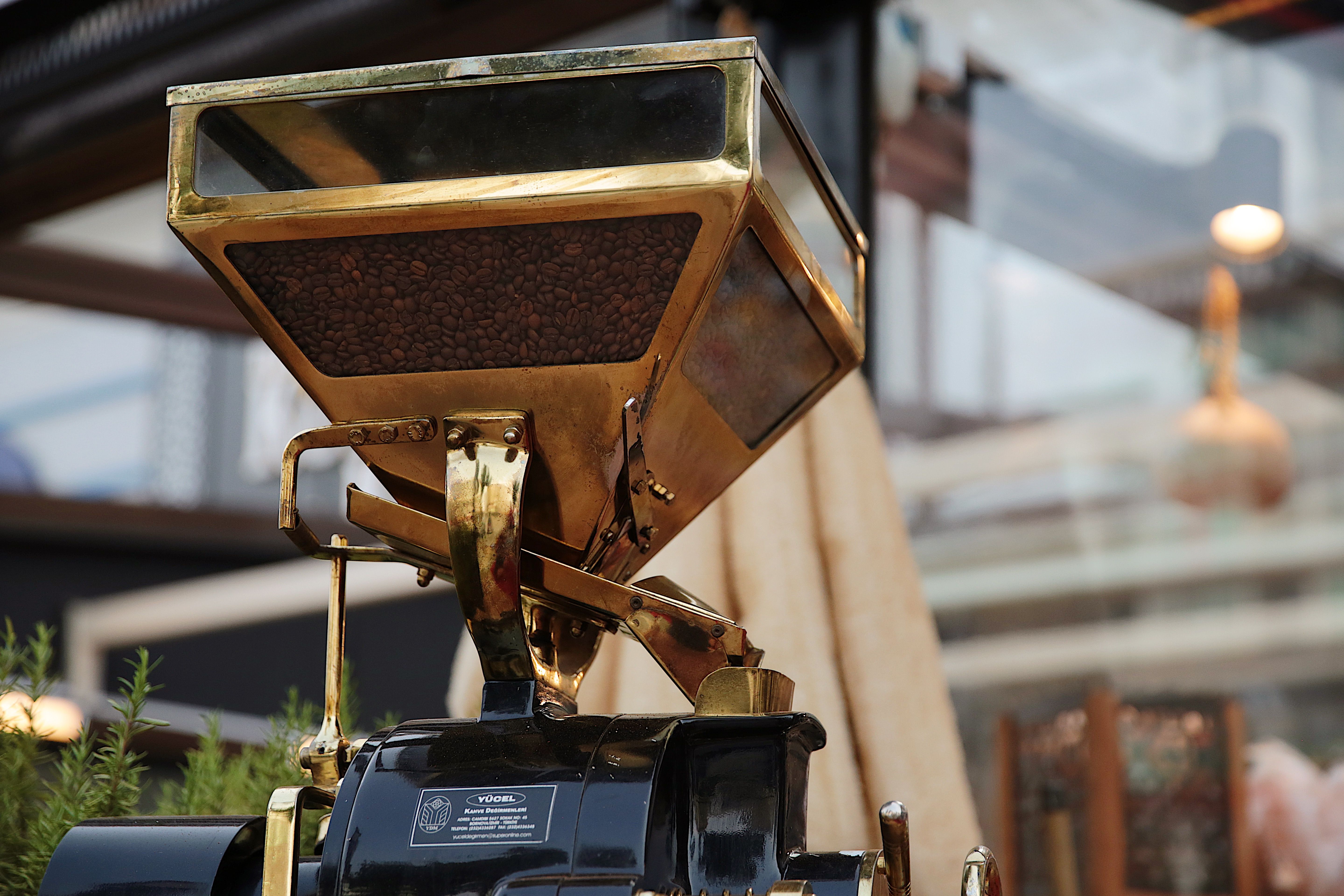 Close-up of a golden coffee grinder filled with coffee beans, showcasing rich details.