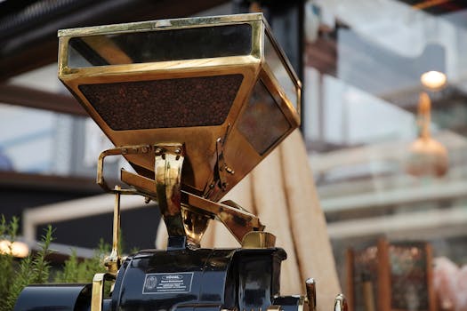 Close-up of a golden coffee grinder filled with coffee beans, showcasing rich details.