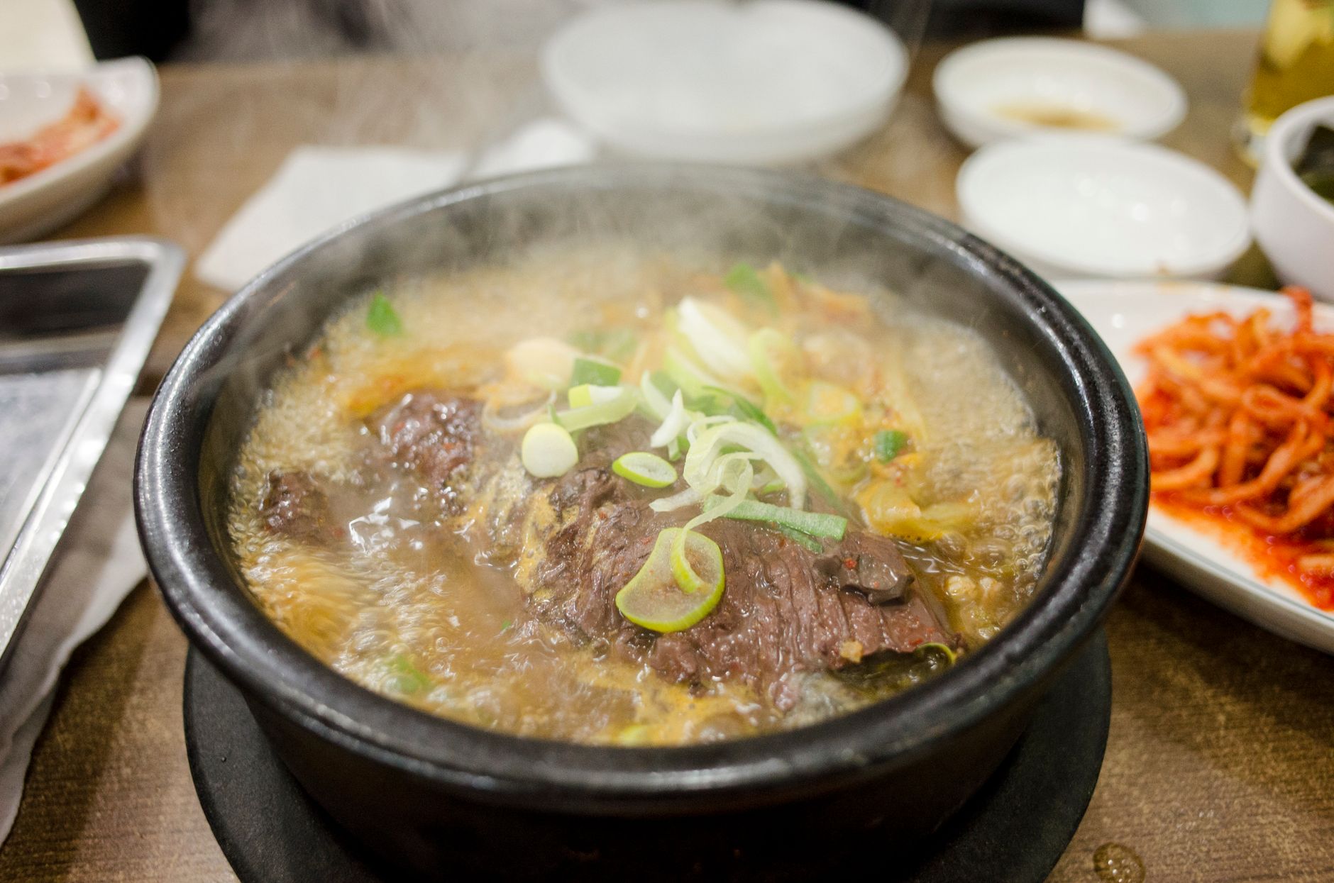 冬天不想出門,小鍋5分鐘煮熱湯 Delicious steaming beef stew in a traditional Korean hot stone pot, garnished with fresh scallions.