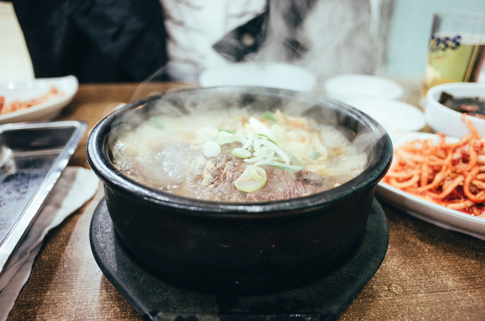 Close-up of a steaming bowl of Asian soup with side dishes, perfect for warmth and comfort food lovers.