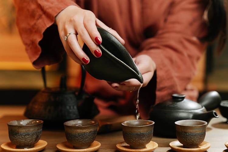 Woman Hand Holding Container And Pouring To Cups