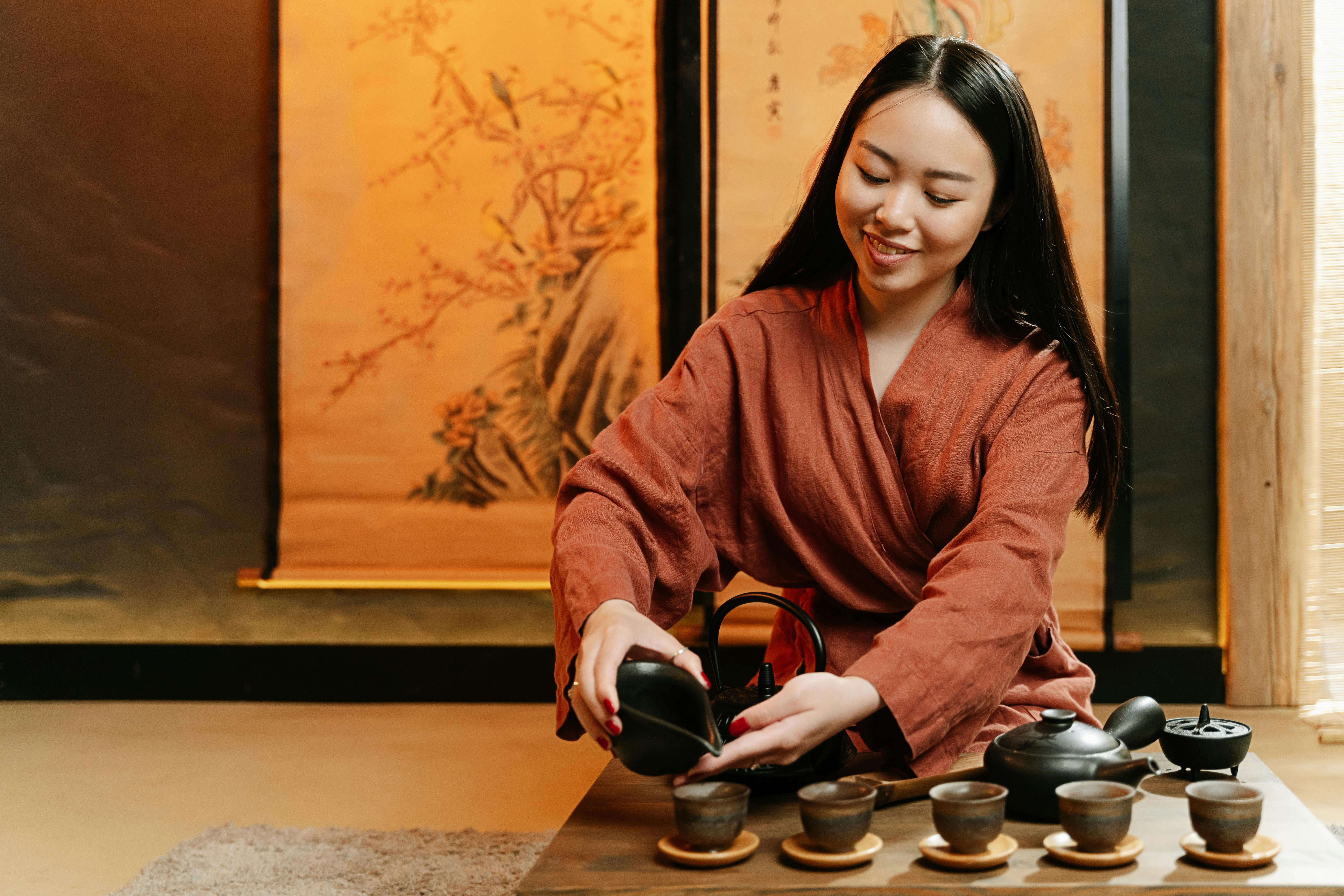 a woman in a robe pouring tea on teacup