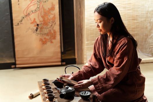 An Asian woman performing a traditional tea ceremony with a focus on cultural elegance.