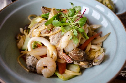 Delicious seafood pasta with prawns, clams, and fresh herbs in a bowl.
