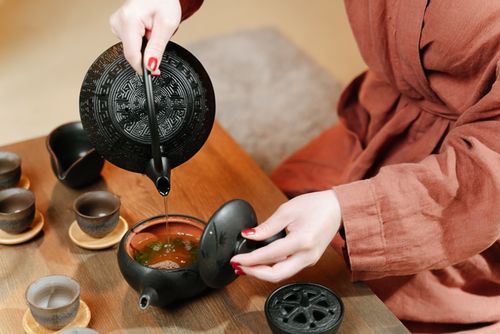 Free Close-up of a traditional tea ceremony featuring black teaware and a person pouring tea. Stock Photo