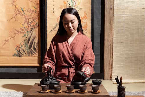 Woman in Red and White Robe Holding Black Ceramic Cup