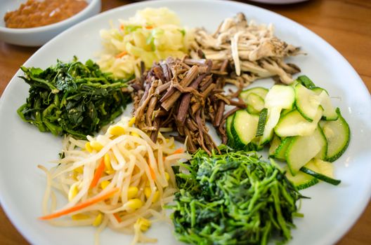 A vibrant assortment of traditional Korean side dishes including vegetables and bean sprouts.