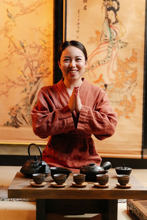 Free Asian woman in red robe enjoys a traditional tea ceremony indoors. Stock Photo