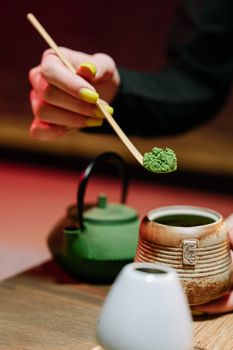 A detailed view of a matcha tea ceremony with hands preparing traditional green tea.