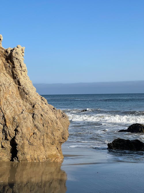 Sandy beach near sea and rocky formations