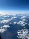 View from plane porthole of sky with clouds above valley