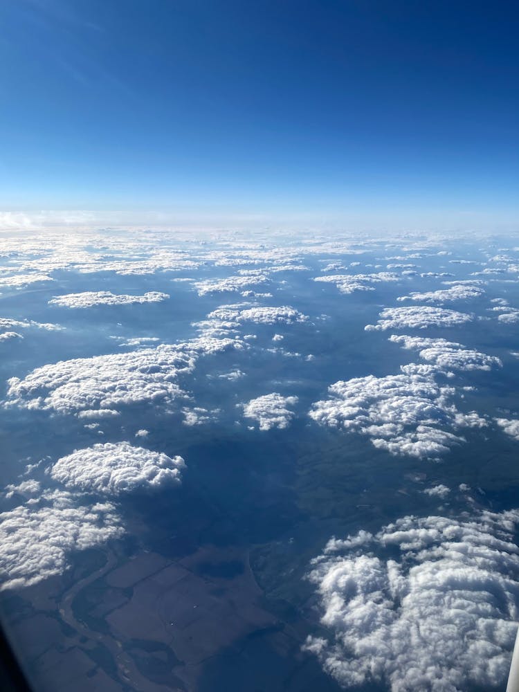 View From Plane Porthole Of Sky With Clouds Above Valley