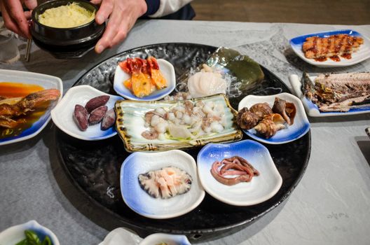 A selection of fresh and cooked seafood on assorted plates, showcasing traditional Asian cuisine.