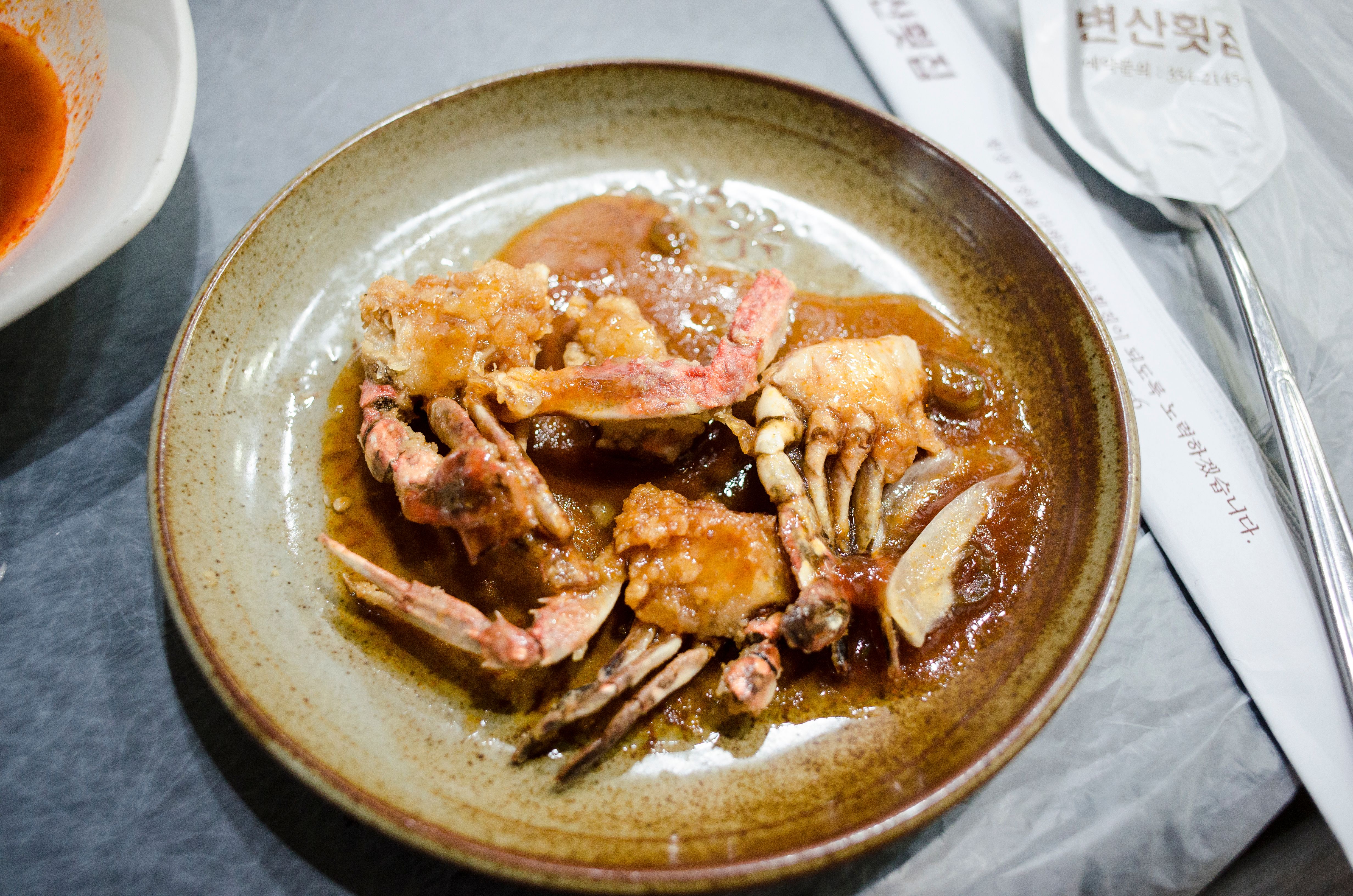 Appetizing close-up of marinated crab dish on a ceramic plate, showcasing Korean cuisine.