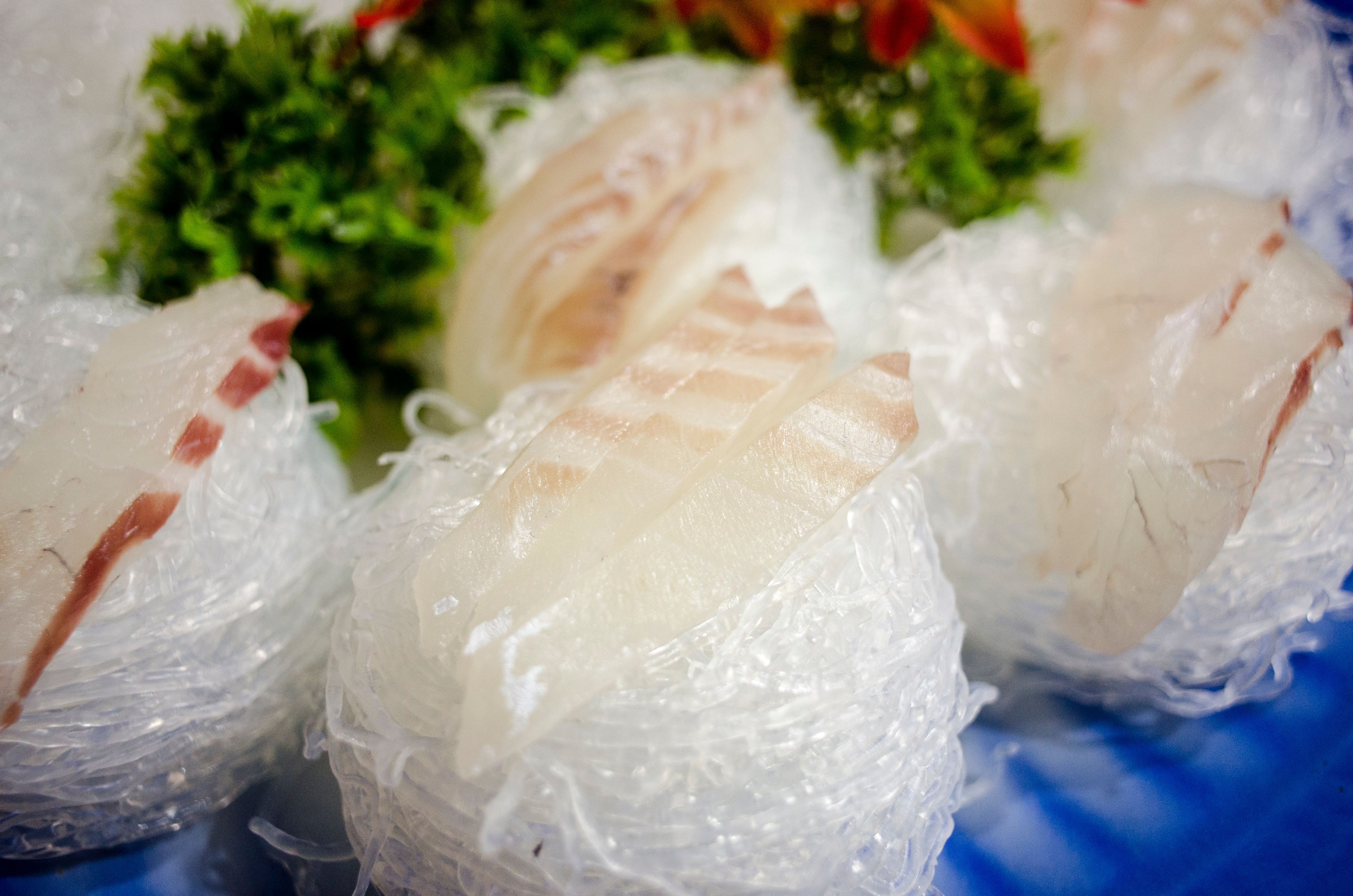 Delicious sashimi slices beautifully presented on a bed of ice with fresh garnish, ideal for food photography.