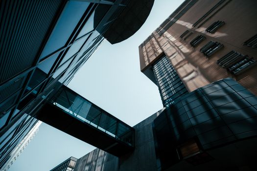 Dynamic low-angle shot of modern buildings with sky and dramatic shadows, emphasizing architecture.